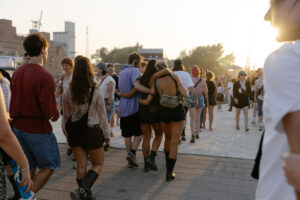 MS Dockville. Auf dem Bild sind Menschen zu sehen, die sich im Arm halten und über das Gelände laufen